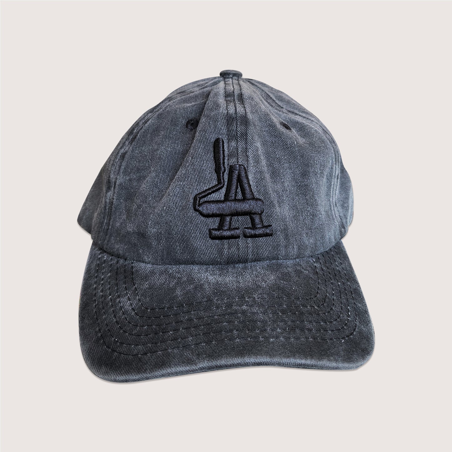 Locally branded unstructured cap in acid-washed black with black puff embroidery detail.